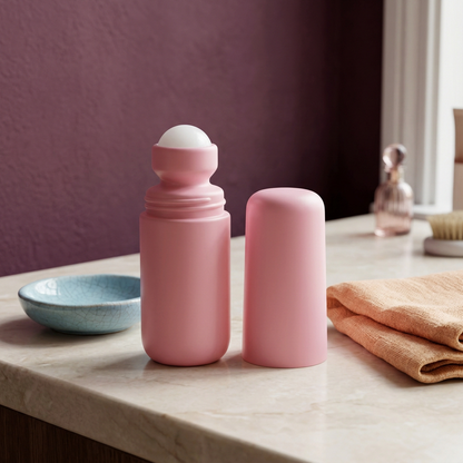 Pink roll-on serum in a colorful personal care still life